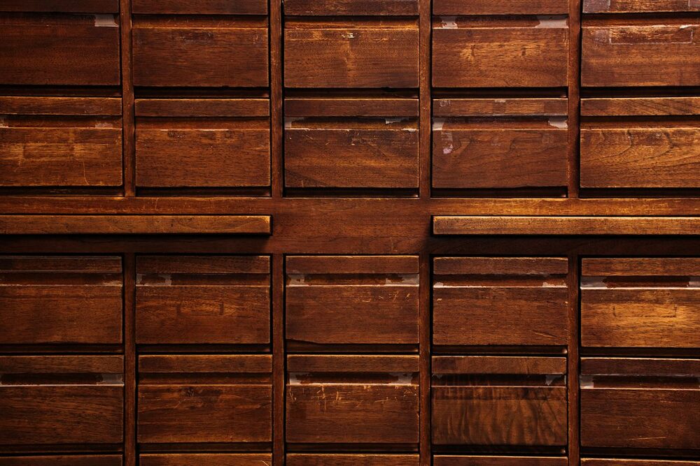 Where a comedian profile is filed: a wall of old wooden index drawers in warm light