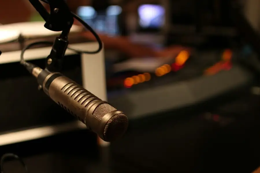 A broadcast microphone on an arm in a dim home studio: posting comedy clips