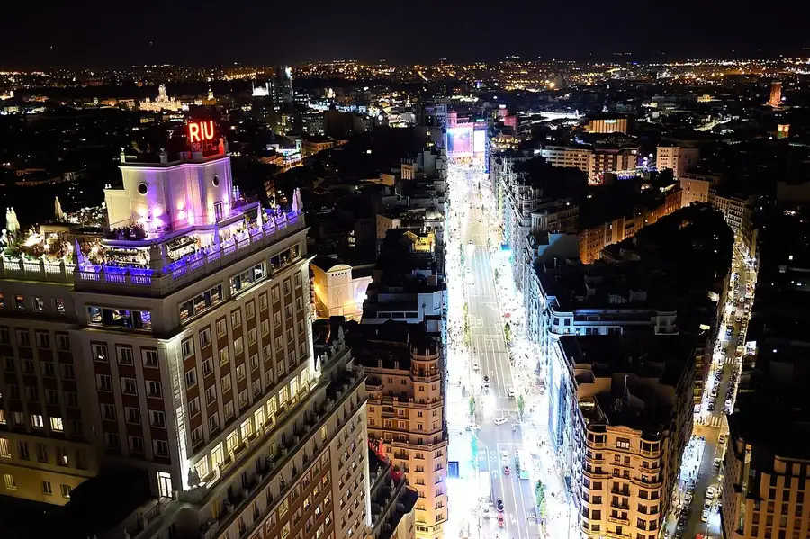 Stand-up comedy in Spain: Madrid's Gran Vía at night seen from above, lit from end to end, with the Edificio España in the foreground