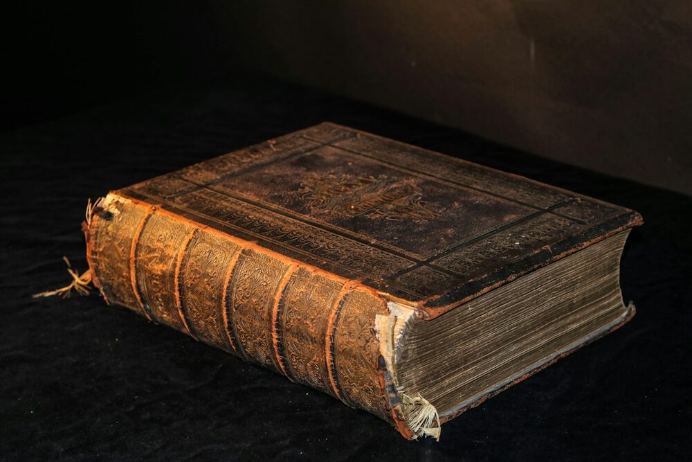 The SUCDb records, pictured as an old leather-bound book with a tooled spine, lit warm on black cloth