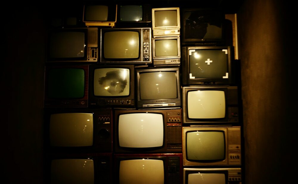 Screen Stars, the actors who are comedians: a wall of stacked vintage television sets glowing warm in the dark