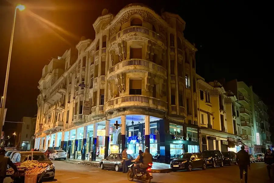 Stand-up comedy in Morocco: an Art Deco corner building in Casablanca lit gold at night above the street