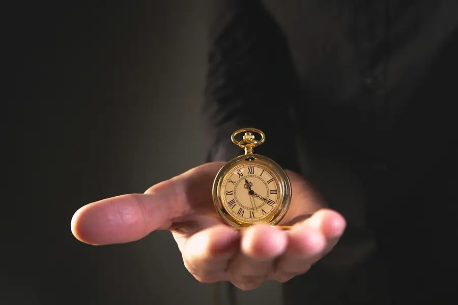 A gold pocket watch held in an open palm: show night