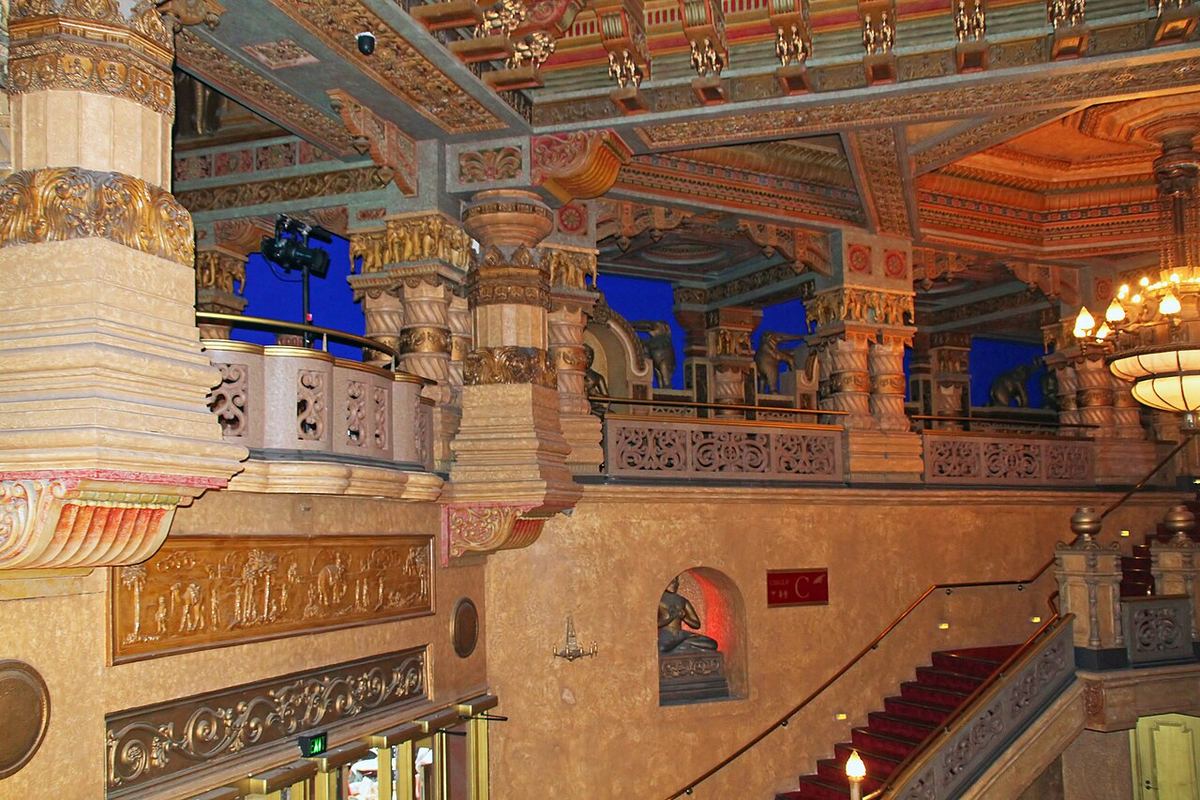 Stand-up comedy in New Zealand: the gilded foyer of the Civic Theatre in Auckland, its carved balconies, chandelier and red-carpeted stair lit warm