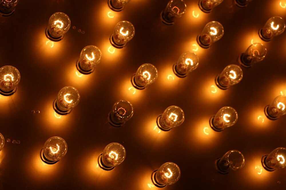 A marquee for the Comedy Calendar: bare amber bulbs glowing on a dark panel