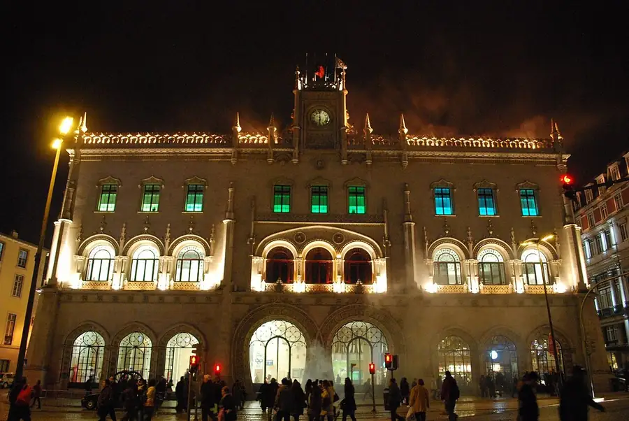 Stand-up comedy in Portugal: Rossio station in Lisbon at night, its horseshoe arches and clock tower lit gold above the square