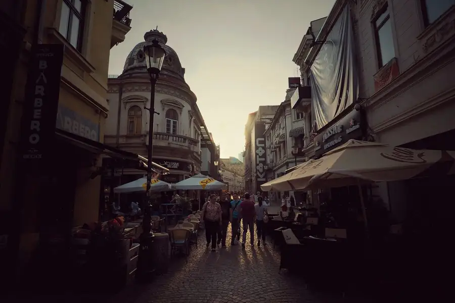 Stand-up comedy in Romania: Lipscani Street in Bucharest's Old Town at sunset, its café terraces full under ornate old facades