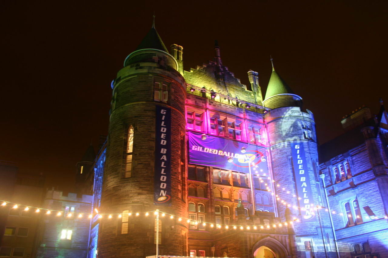 Stand-up comedy in Scotland: Teviot Row House in Edinburgh lit in pink, blue and gold for the Edinburgh Festival Fringe