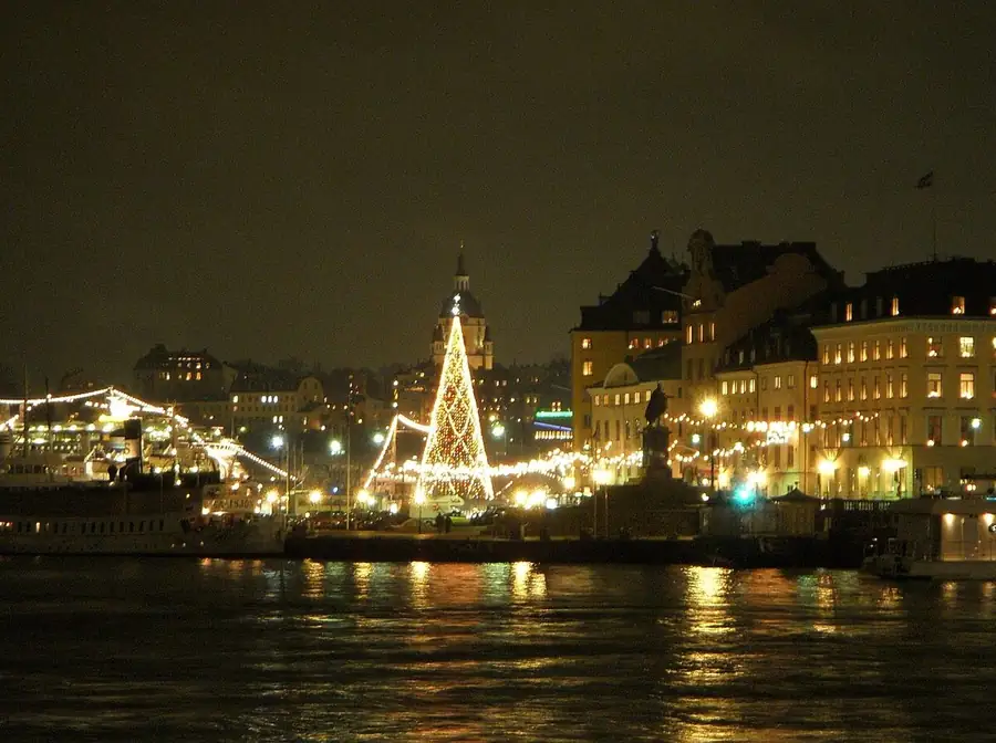 Stand-up comedy in Sweden: Stockholm's Gamla stan across the water at night on the first Sunday of Advent, a lit Christmas tree and strings of lights along the quay